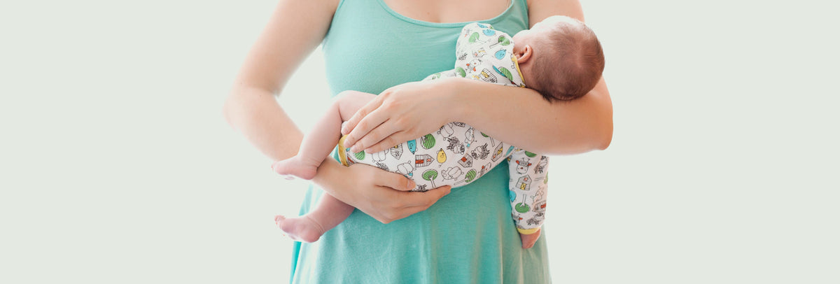 Mom in a turquoise dress holding a newborn baby in her arms